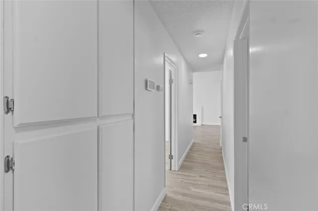 a view of a hallway with wooden floor and a bathroom