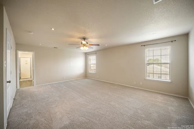 an empty room with chandelier fan and windows