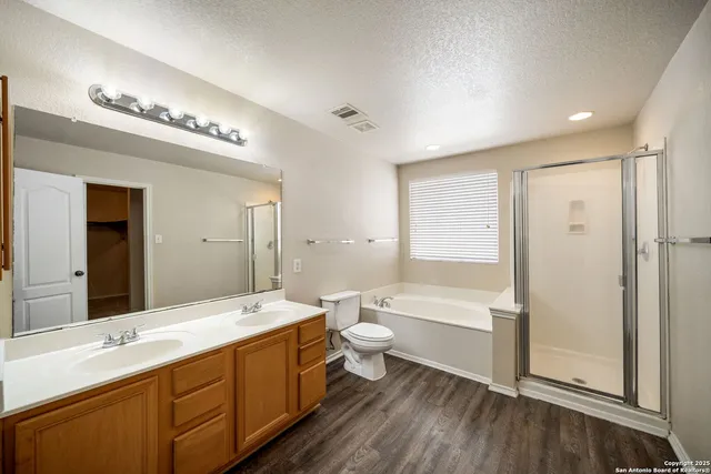 a bathroom with a double vanity sink a toilet and shower