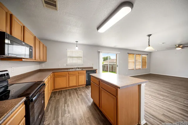 a kitchen with stainless steel appliances granite countertop a stove and a wooden floors