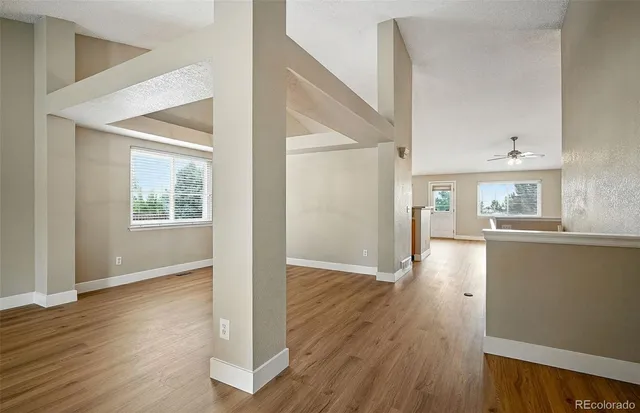 an empty room with wooden floor and windows