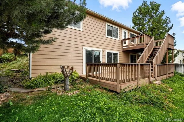 a view of a house with a small yard and wooden deck