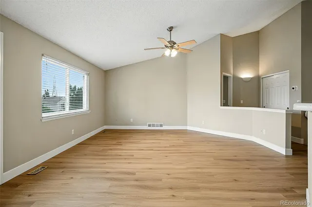 a view of an empty room with window and wooden floor