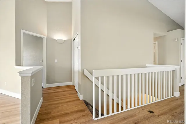a view of a hallway with wooden floor and a bathroom