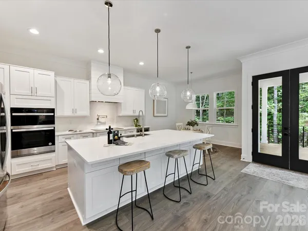 a kitchen with stainless steel appliances granite countertop a stove a sink a oven a dining table and chairs with wooden floor