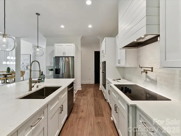 a kitchen with stainless steel appliances a sink a stove a refrigerator a center island and windows