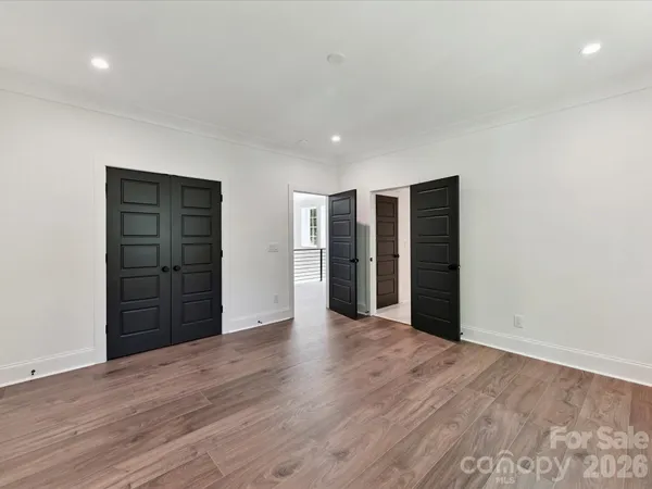 a view of an empty room with closet and wooden floor