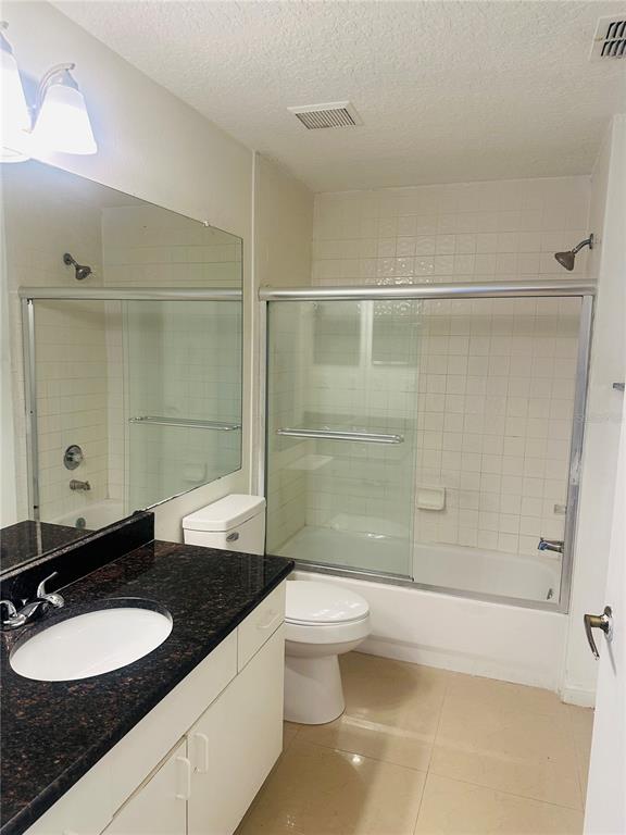 5560 Metrowest Boulevard, Unit 101 Orlando, FL 32811 - Photo 15 of 30 a bathroom with a granite countertop sink toilet a mirror and shower