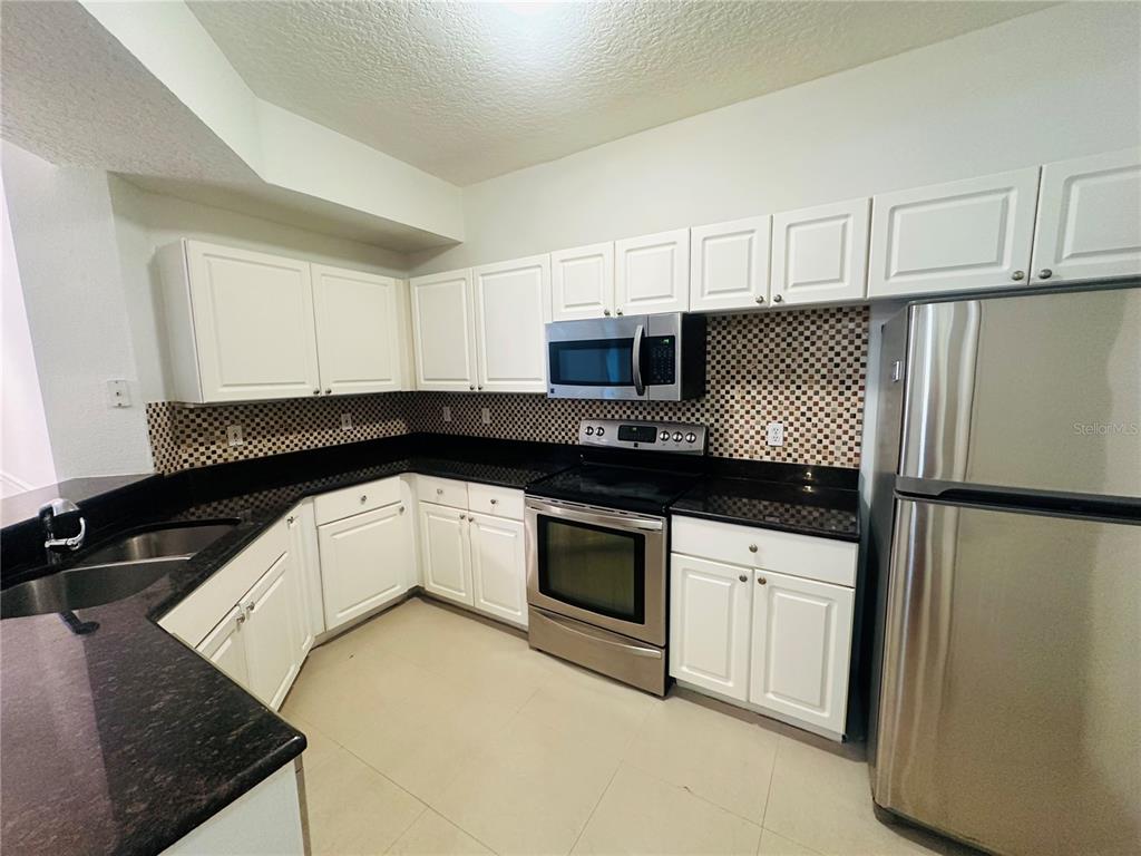 5560 Metrowest Boulevard, Unit 101 Orlando, FL 32811 - Photo 6 of 30 a kitchen with a refrigerator sink and white cabinets
