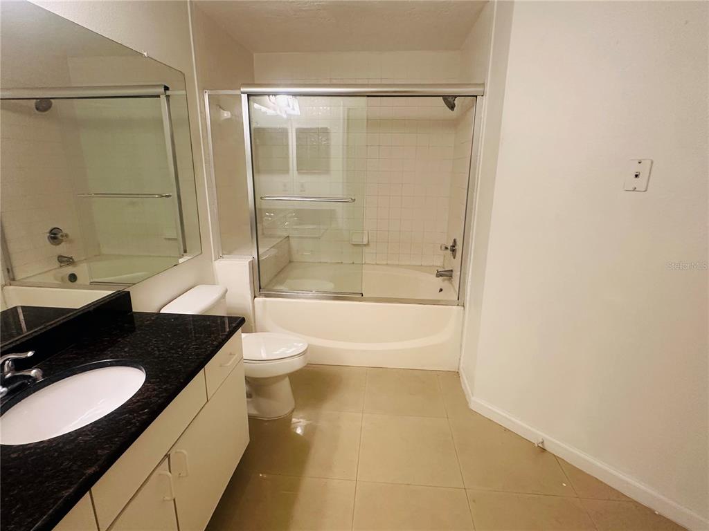 5560 Metrowest Boulevard, Unit 101 Orlando, FL 32811 - Photo 10 of 30 a bathroom with a granite countertop sink toilet a bathtub and shower