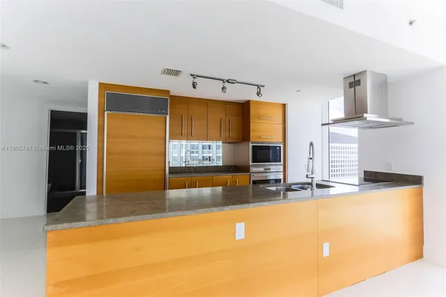 a view of a kitchen with stainless steel appliances granite countertop a sink and a refrigerator