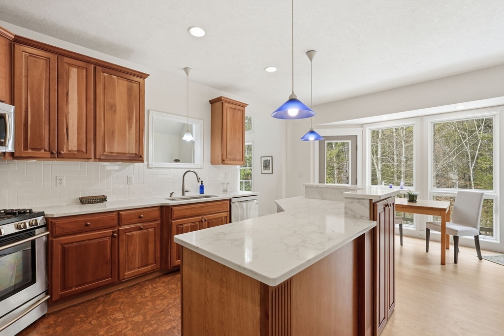 16 North Valley Road Pelham, MA 01002 - Photo 13 of 41 a kitchen with a stove a sink a dining table and chairs with wooden floor