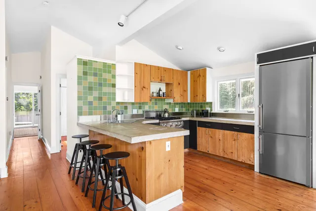 a kitchen with stainless steel appliances a table chairs refrigerator and wooden floor