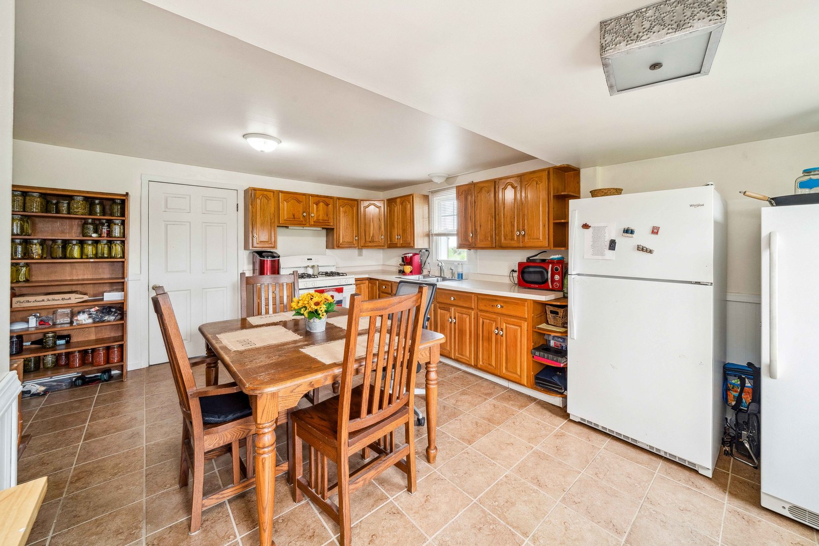 15589 Chicago Road Sandwich, IL 60548 - Photo 6 of 30 a kitchen with a refrigerator a stove a dining table and chairs
