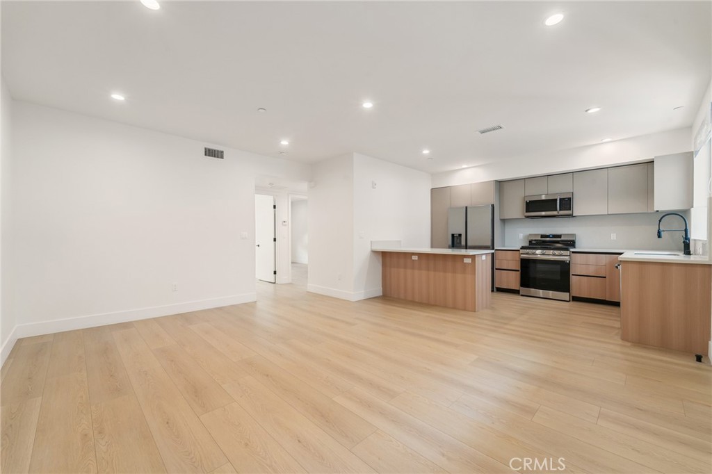 7510 Sepulveda Boulevard, Unit 204 Van Nuys, CA 91405 - Photo 11 of 24 a large kitchen with stainless steel appliances a large counter top a oven and a sink with granite countertops