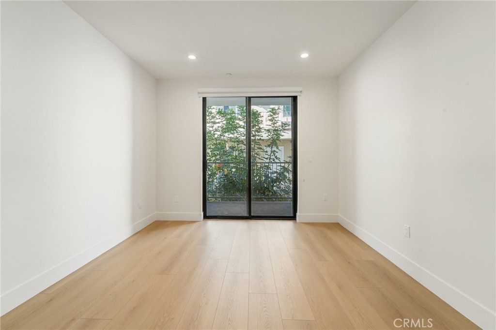 7510 Sepulveda Boulevard, Unit 204 Van Nuys, CA 91405 - Photo 17 of 24 a view of an empty room with wooden floor and a window