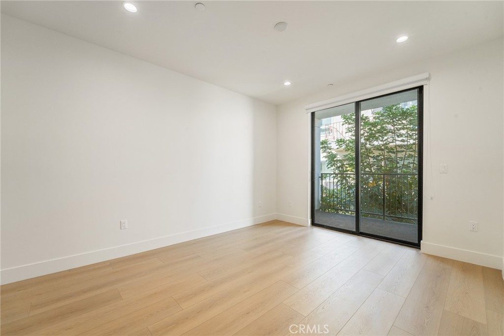 7510 Sepulveda Boulevard, Unit 204 Van Nuys, CA 91405 - Photo 18 of 24 an empty room with wooden floor and windows