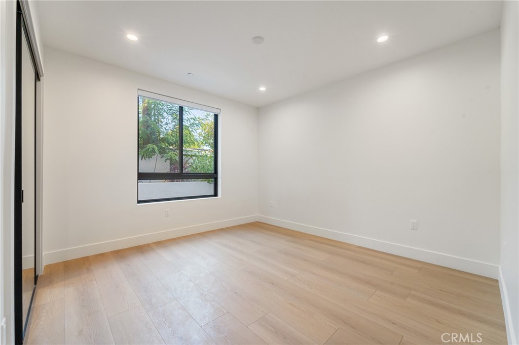 7510 Sepulveda Boulevard, Unit 204 Van Nuys, CA 91405 - Photo 20 of 24 an empty room with wooden floor and windows