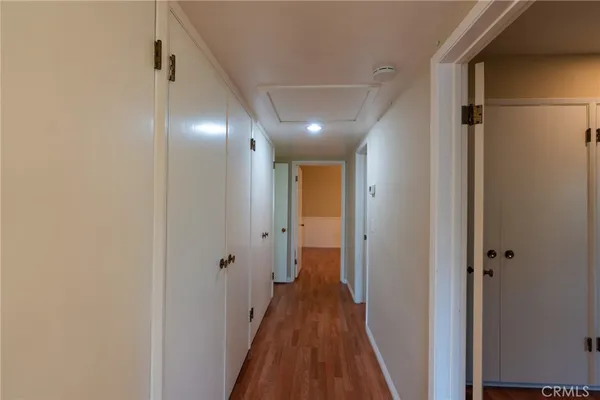 a view of a hallway with wooden floor and a bathroom