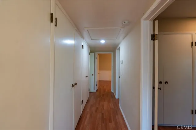 a view of a hallway with wooden floor and a bathroom