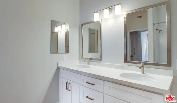 a bathroom with double vanity sinks and a mirror