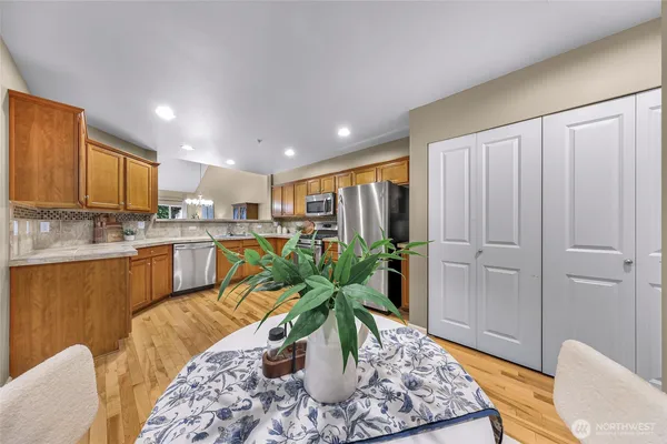 a living room with stainless steel appliances furniture windows and a kitchen view