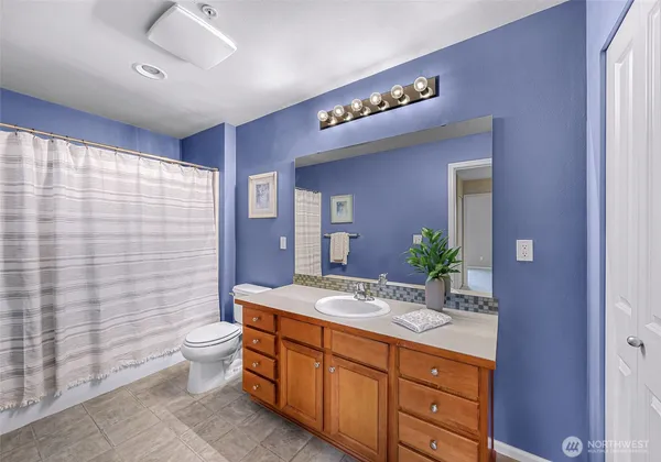 a spacious bathroom with a granite countertop sink a toilet a mirror and shower curtain