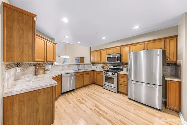 a kitchen with granite countertop stainless steel appliances a refrigerator cabinets and a large window