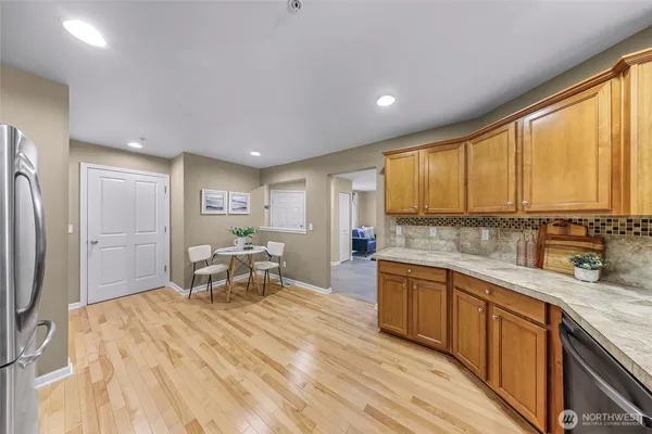 a open kitchen with stainless steel appliances granite countertop a refrigerator a sink dishwasher a stove and white countertops with wooden floor