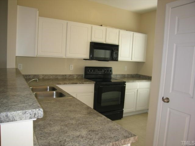 5948 Osprey Cove Drive Raleigh, NC 27604 - Photo 4 of 12 a kitchen with granite countertop a sink and white cabinets