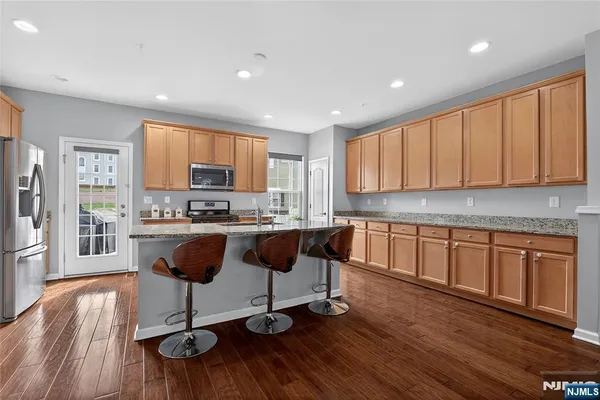 a kitchen with stainless steel appliances granite countertop a stove a sink a refrigerator and cabinets with wooden floor