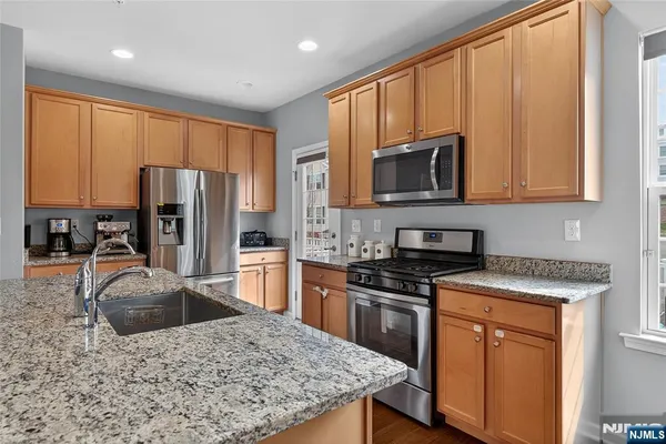 a kitchen with stainless steel appliances granite countertop a stove a sink dishwasher a refrigerator and cabinets with wooden floor