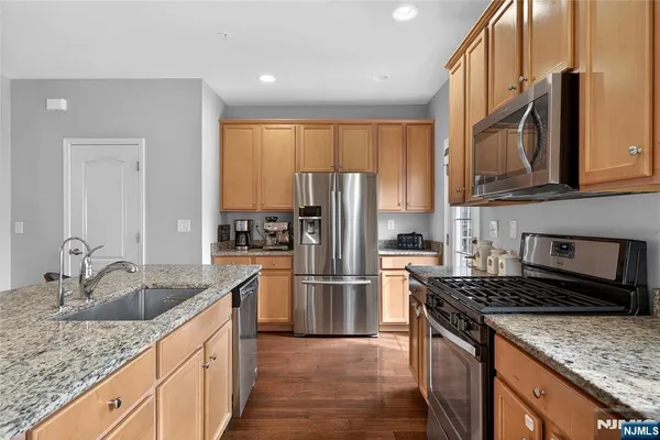 a kitchen with granite countertop a refrigerator stove and sink