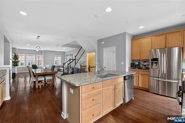 a kitchen with a table chairs refrigerator and wooden floor