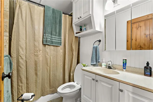 a bathroom with a sink a toilet a mirror and shower curtain