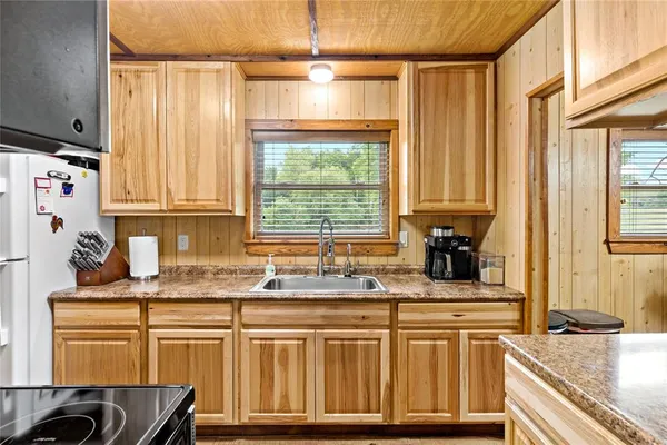 a kitchen with stainless steel appliances granite countertop a sink a stove and a wooden cabinets