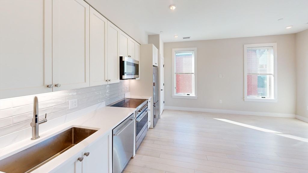 197 Green Street, Unit 401 Boston, MA 02130 - Photo 2 of 5 a kitchen with a sink stove and microwave