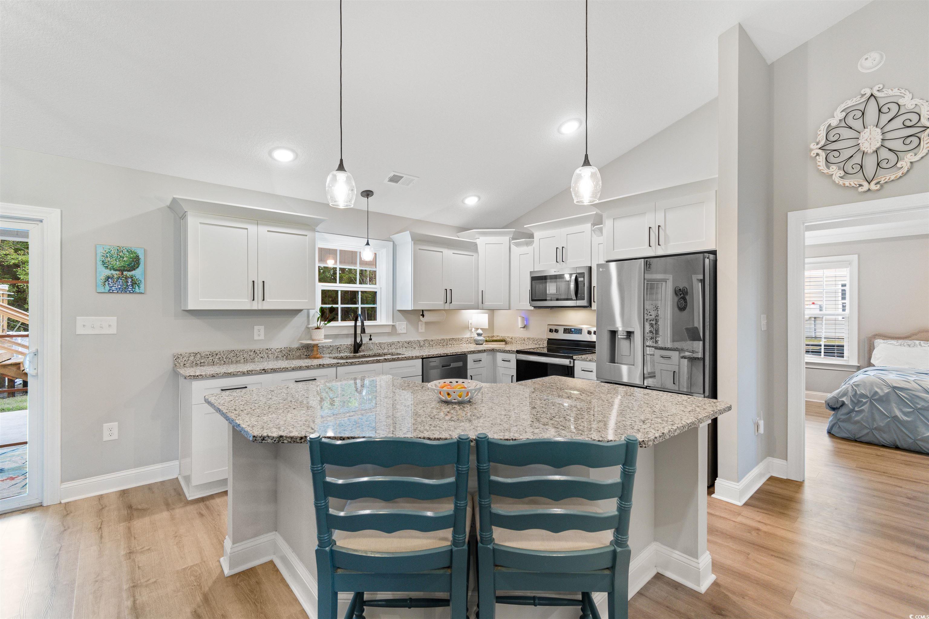 Kitchen with white cabinetry, appliances with stai