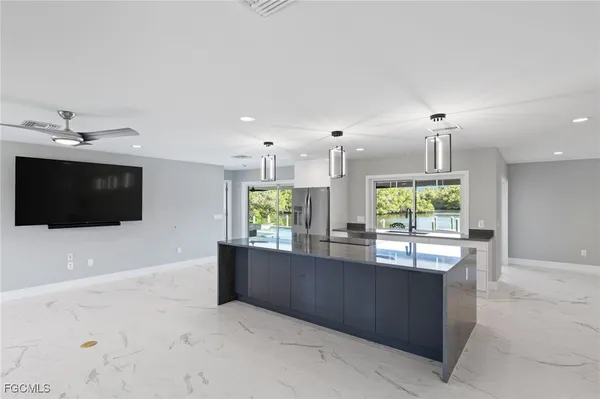 a kitchen with kitchen island large windows and refrigerator