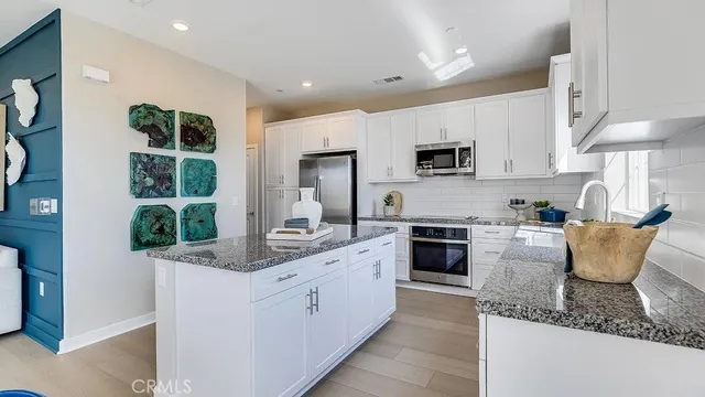 a kitchen with stainless steel appliances granite countertop a stove top oven a sink a microwave and a refrigerator