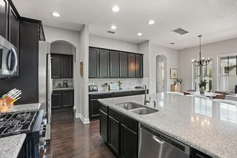 a kitchen with stainless steel appliances granite countertop a sink a stove and a refrigerator