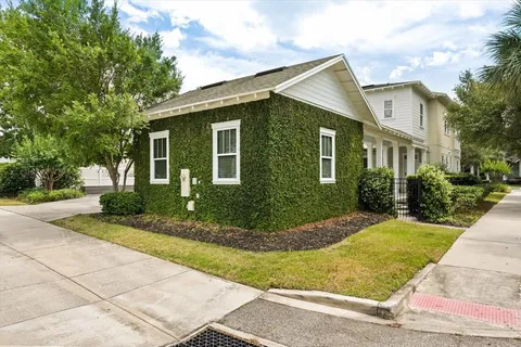 a view of a house with brick walls plants and large tree