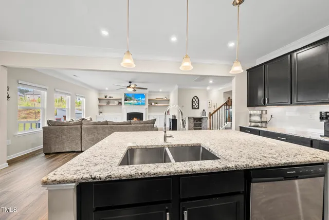 a kitchen with kitchen island a sink stainless steel appliances and living room view