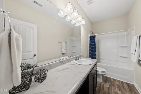 a bathroom with a granite countertop sink a toilet and shower