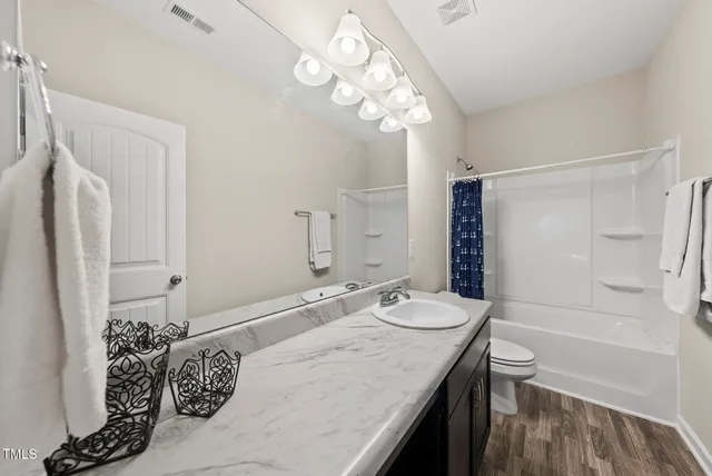 a bathroom with a granite countertop sink a toilet and shower