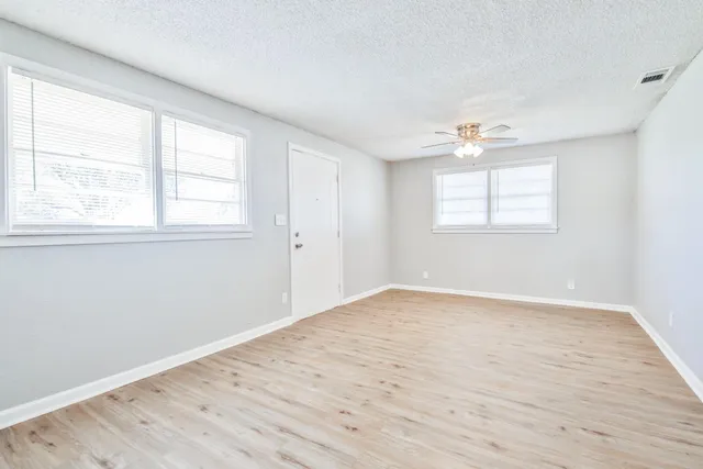 an empty room with wooden floor and windows