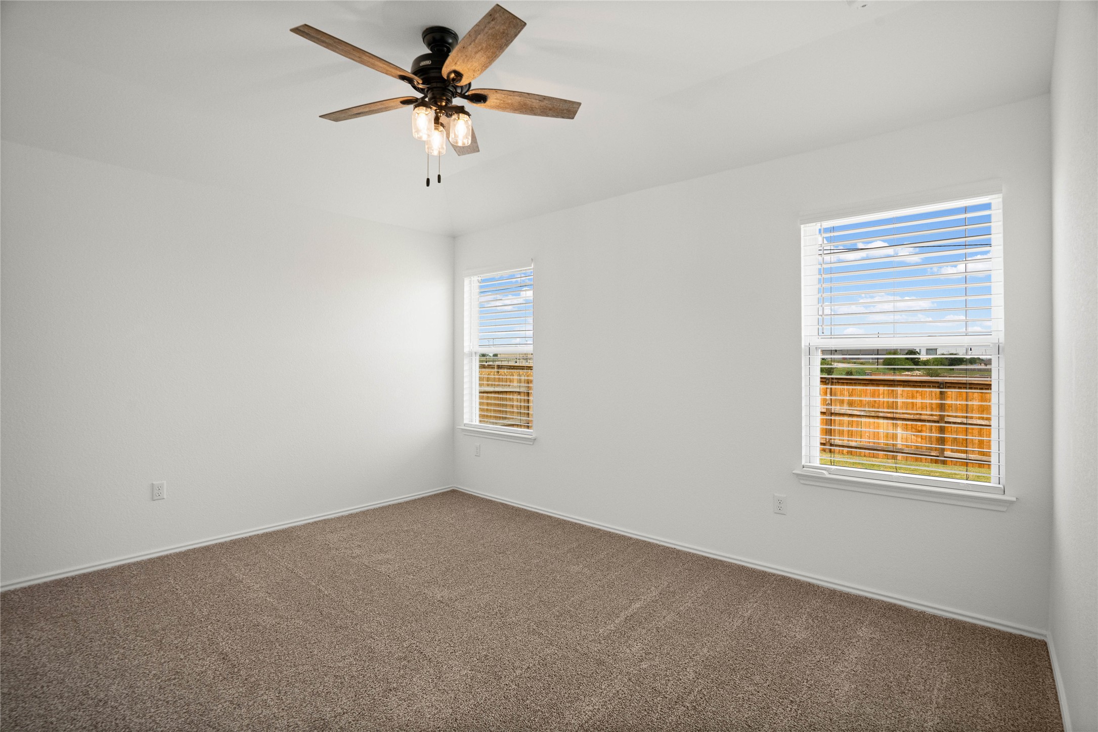 15004 Welsh Cobb Rd Manor, Unit A Manor, TX 78653 - Photo 13 of 22 Carpeted interior room featuring two windows with horizontal blinds, a ceiling fan with light fixture, and white painted walls