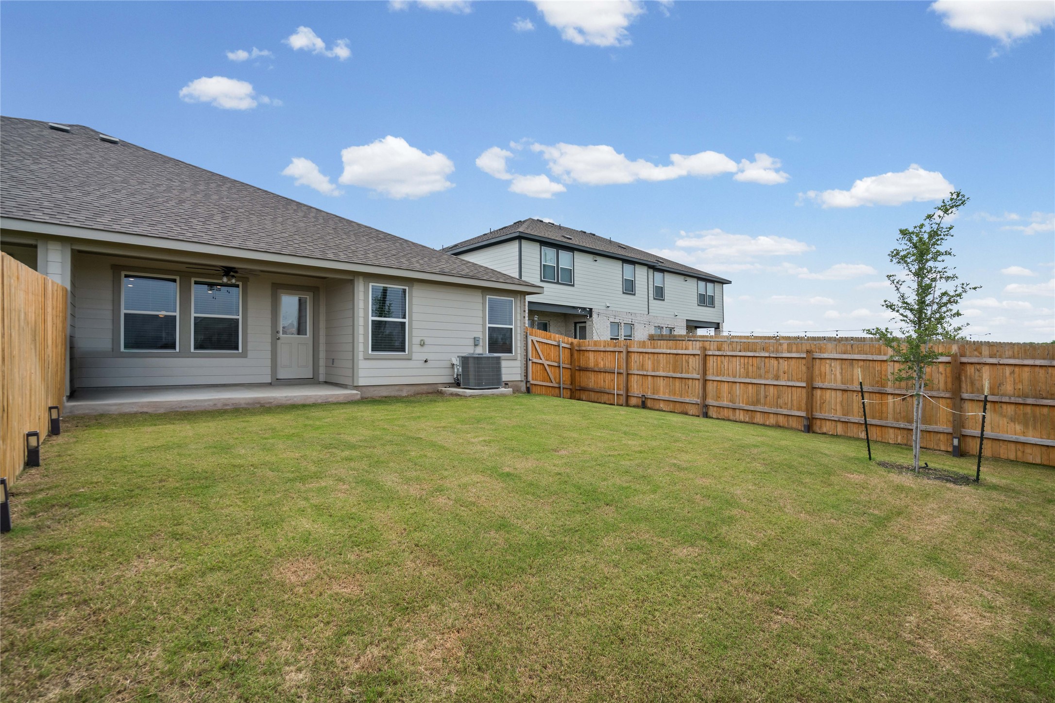 15004 Welsh Cobb Rd Manor, Unit A Manor, TX 78653 - Photo 18 of 22 Spacious backyard featuring a manicured lawn, full privacy fencing, and a young tree
