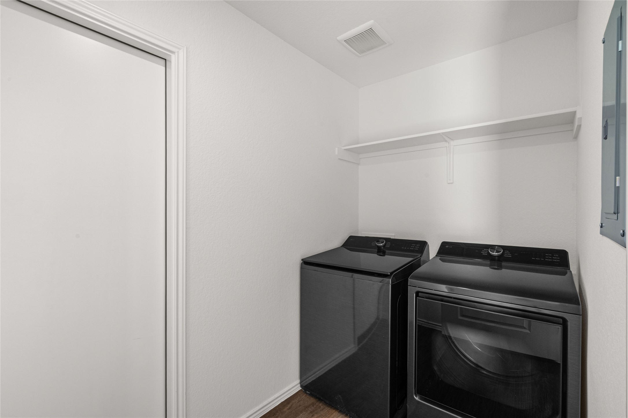 15004 Welsh Cobb Rd Manor, Unit A Manor, TX 78653 - Photo 5 of 22 Dedicated laundry area featuring a white wall shelf, textured white walls, and wood-finish flooring
