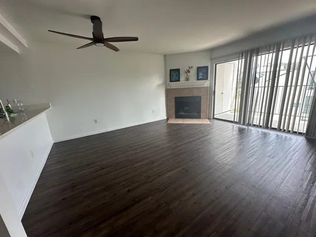 a view of a livingroom with wooden floor a ceiling fan and windows